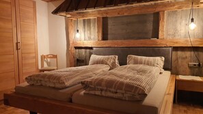 Un lit en bois avec une tête de lit, deux tables de chevet, une chaise et une armoire dans une chambre au style rustique.