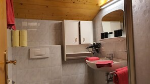 A bathroom with a wooden ceiling, a white sink with a red towel, a white cabinet, and a mirror. - Cozy Angererhof: Close to Drei Zinnen - Monte Paterno (4P) - FRIENDLY (Kartitsch)