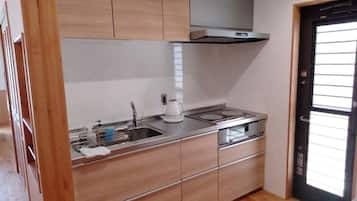 Een koelkast, een magnetron, een kookplaat, kookgerei, borden en bestek