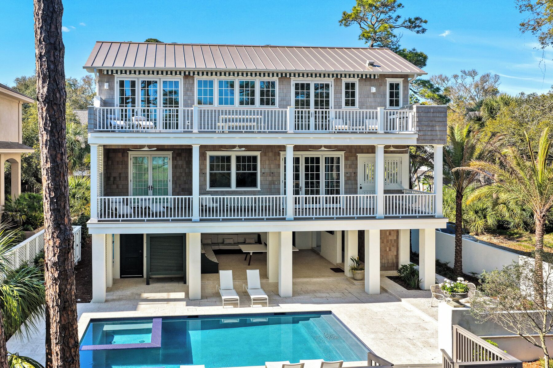 Ein zweistöckiges Haus mit Pool, Balkonen und einer überdachten Terrasse.