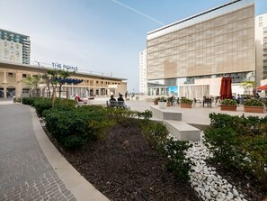 Ein Hotelinnenhof mit Außenbestuhlung, einem Springbrunnen und einem großen Gebäude mit Glasfassade.