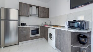 Een moderne keuken met een roestvrijstalen koelkast, inbouwoven, magnetron en wasmachine.