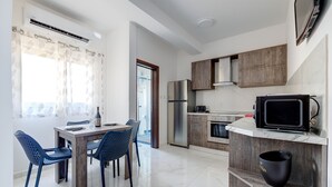 A modern kitchen with a built-in oven, a microwave, and a refrigerator. There is a dining area with a table and chairs. - Idyllic Apartment steps from the Promenade (Gzira)