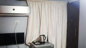 A compact kitchenette with a refrigerator, a coffee maker, and a small table. - Downtowninn (Cairo)