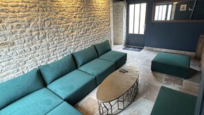 Un área de estar moderna con una pared de piedra, sofás verdes, una mesa de centro redonda y un aplique de techo.