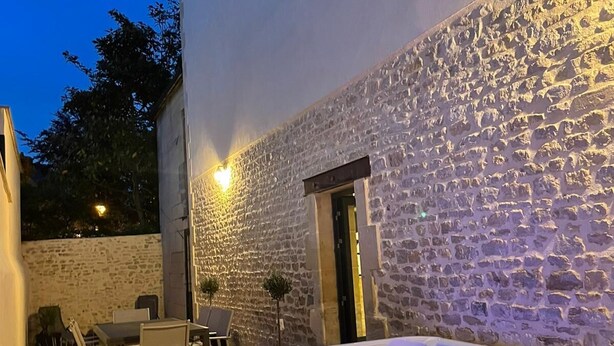 Un espacio al aire libre con paredes de piedra, un jacuzzi, una mesa y sillas.