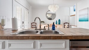 Una cocina con dos fregaderos, una araña y un lavavajillas Samsung.