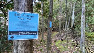 A sign on a tree in a forested area, indicating the Beth Gilhapy Side Trail, with a length of 3.4 km.
