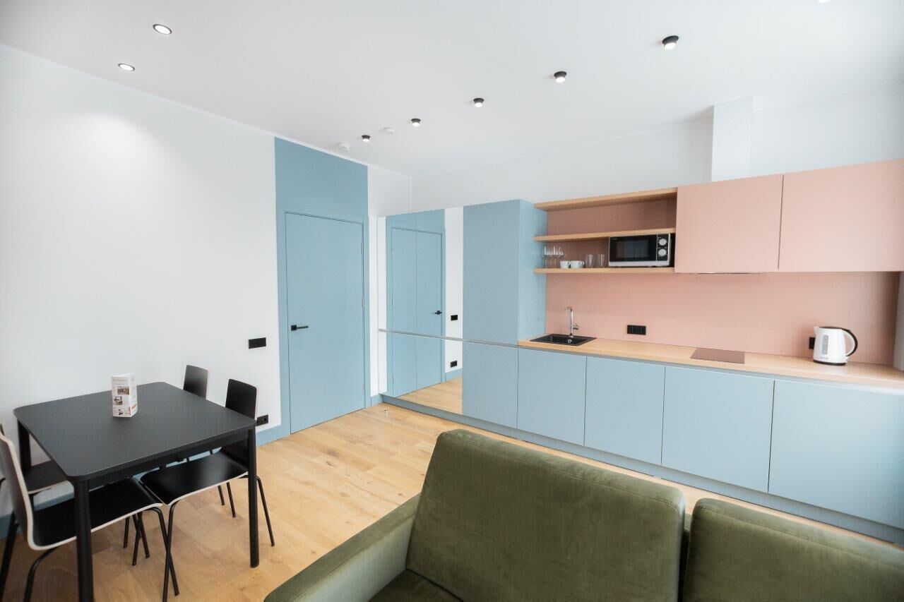 Una cocina compacta con comedor, microondas y tetera.