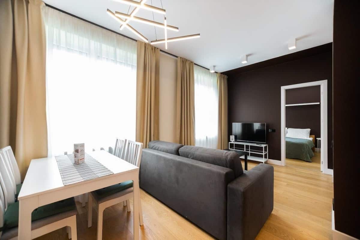 A modern living room with a sofa, a dining table, and a TV.