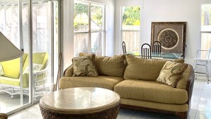 A living room with a beige sectional sofa, a round coffee table, and a ceiling fan.