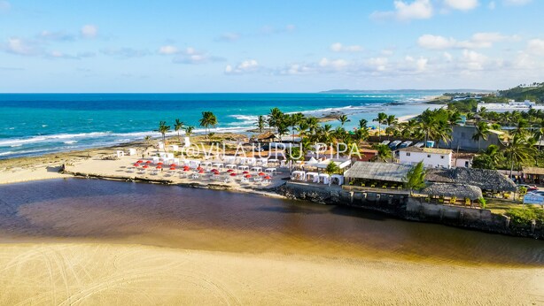 Um resort à beira-mar com espreguiçadeiras, guarda-sóis e vista para o oceano.
