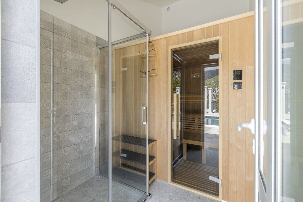 A modern bathroom with a glass shower enclosure, wooden paneling, and a built-in bench.