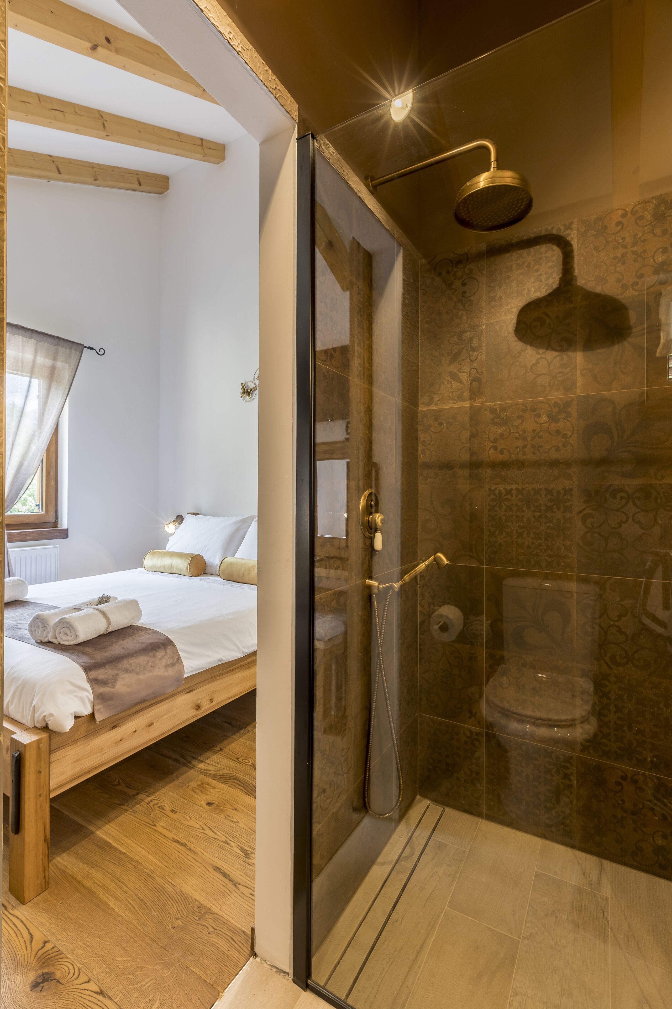 A bedroom with a wooden bed, a glass shower enclosure, and a bathroom with a toilet and shower.