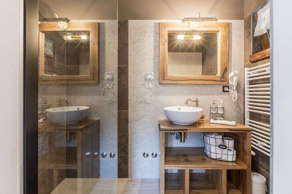 A modern bathroom with two sinks, a wooden vanity, and a mirror.