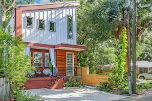 A two-story house with a red and white exterior, a front porch with a staircase, and a fenced backyard. - Stylish Lincolnville Escape - Walk to Downtown (Saint Augustine)