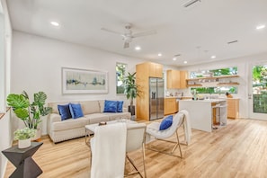 A modern living room with a sofa, chairs, a dining table, a kitchen area, and a ceiling fan. - Stylish Lincolnville Escape - Walk to Downtown (Saint Augustine)