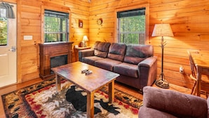 A log cabin interior with a sofa, coffee table, and a fireplace.
