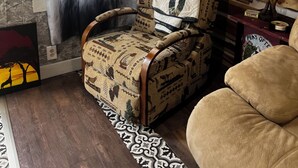 Ein Zimmer mit einem gemusterten Sessel, einer Holzwand mit aufgehängten Geweihen und einem Vorhang mit einem Stiergesicht-Design.