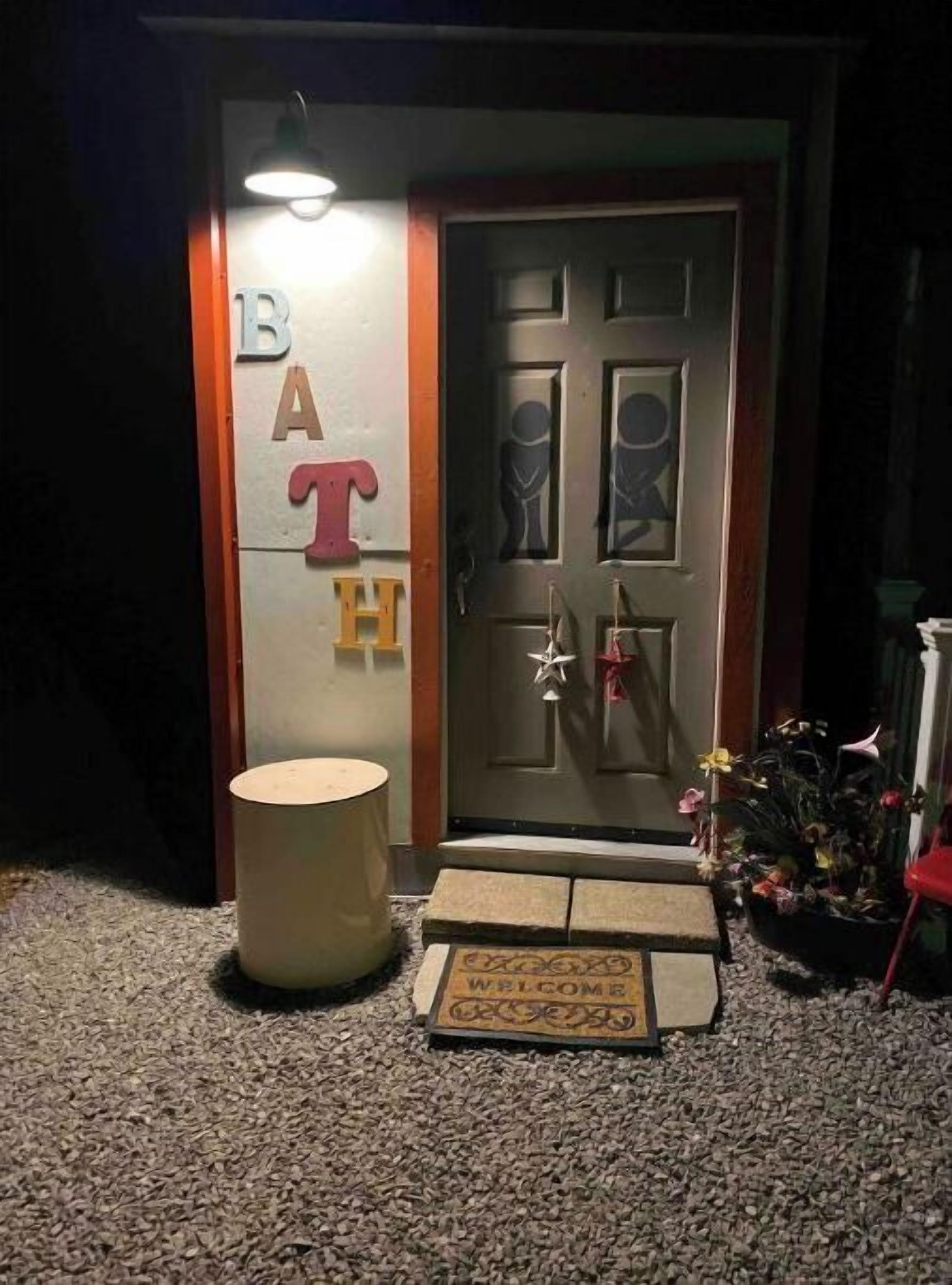 A dark entrance with a door labeled "BATH" and a small round table with a doormat in front.
