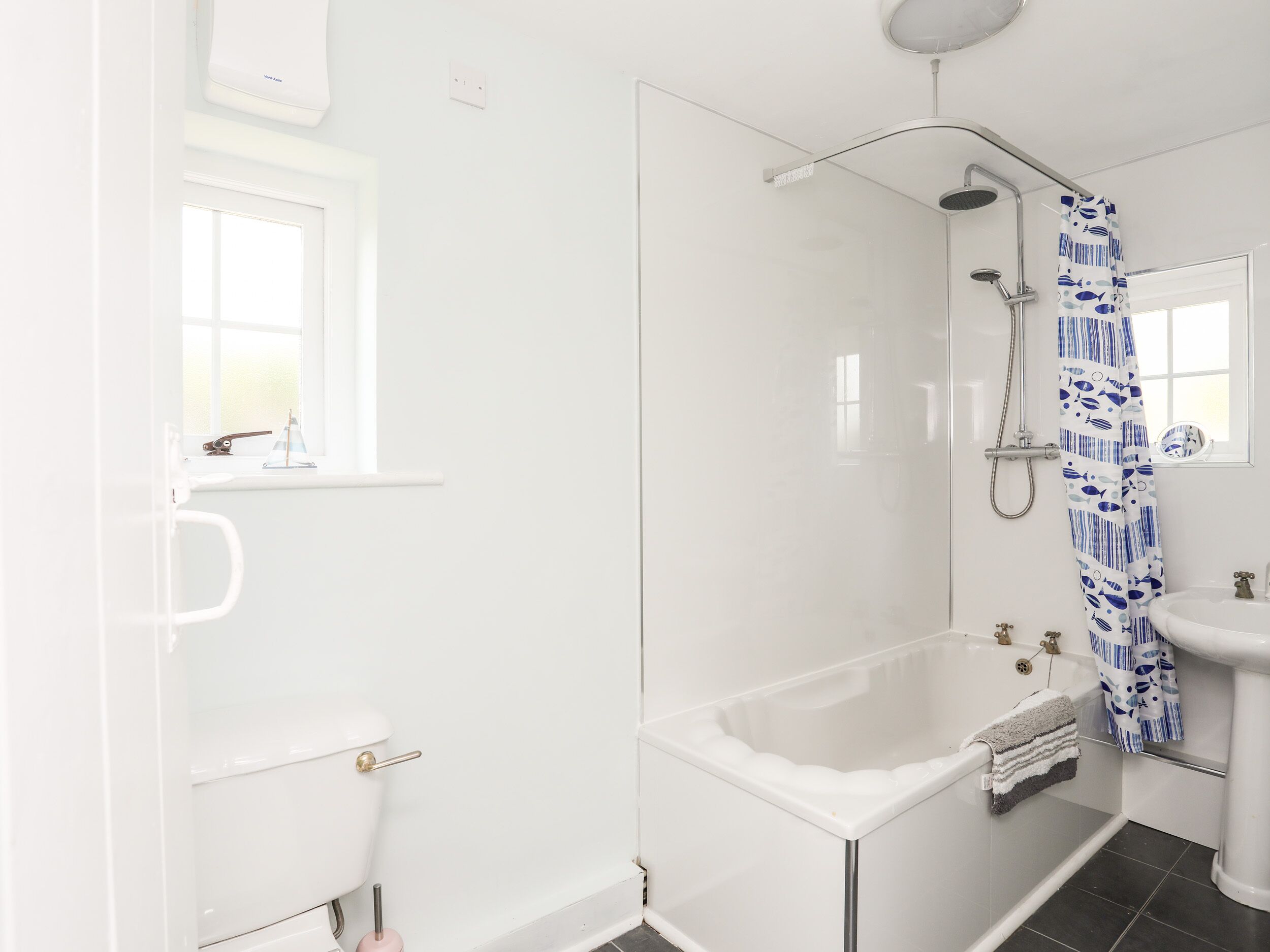 A modern bathroom with a glass-enclosed shower, a white bathtub, and a sink.