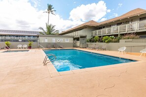 A swimming pool with lounge chairs and a building with a balcony in the background. - Great rates at Kihei Bay Surf G259 Comfortable Studio Space! (Kihei)