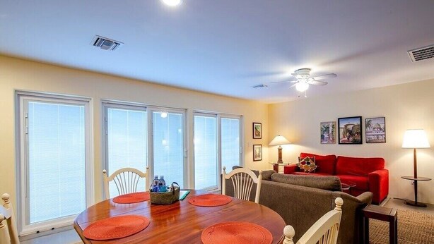 A dining area with a wooden table and chairs, a red sofa, and a ceiling fan. - Solar powered, central, private, secure guest house! (Tucson)