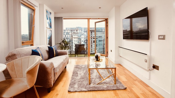Una sala de estar moderna con un sofá, una mesa de centro de vidrio y vistas de la ciudad a través de amplios ventanales.