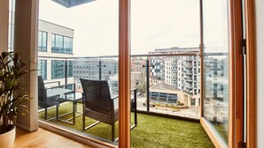Un balcón con vistas a un paisaje urbano, una planta en maceta y una silla moderna.