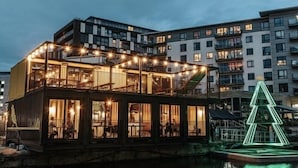 Un edificio frente al agua con varios pisos, ventanas amplias y terrazas al aire libre.