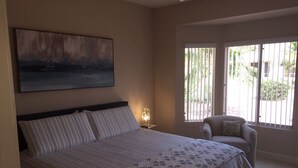 Una camera da letto con un letto, una sedia, un comodino, un quadro e una finestra con persiane.