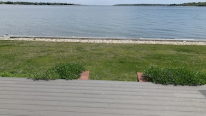 Une vue sur le front de mer, avec une pelouse et une terrasse en bois.