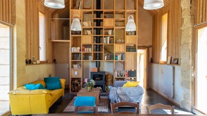 A cozy living room with a yellow sofa, a wooden bookshelf, and a fireplace. - La Grange Milou (Beynac-et-Cazenac)