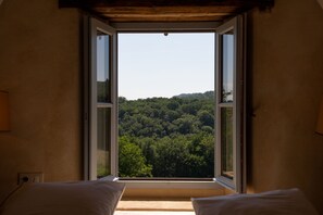 A room with a large window offering a view of a forested hill. - La Grange Milou (Beynac-et-Cazenac)