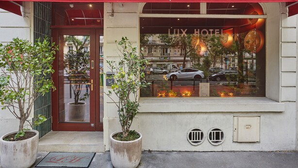 L’extérieur de l’hôtel Lux Picpus se caractérise par un auvent rouge, de grandes fenêtres sur lesquelles est affiché le nom de l’hôtel, et deux plantes en pot placées devant l’entrée.