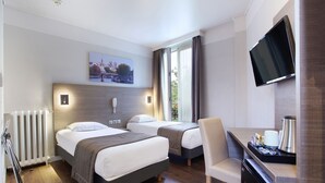 Une chambre d’hôtel avec deux lits, un bureau équipé d’une machine à café, une télévision et une vue sur l’extérieur.