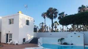 A modern building with a pool, stairs, and palm trees. - Olas de Lobos (Corralejo)