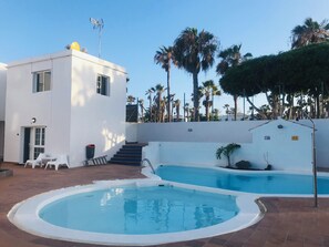 Un edificio moderno con piscina, escaleras y palmeras.