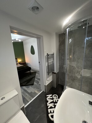 Bathroom features a glass-enclosed shower, bathtub, and towel rack.