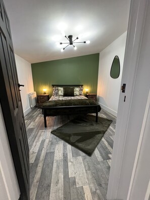 Cozy retreat with a dark headboard bed, bedside tables, and a large oval mirror.