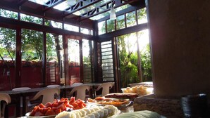A covered outdoor dining area with a variety of fruits and desserts on display. - Mira Maré Praia Hotel (Guarujá)