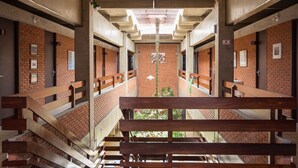 A corridor with brick walls, wooden benches, and a hanging light fixture. - Mira Maré Praia Hotel (Guarujá)