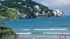 A coastal town with buildings on a hillside overlooking the sea. - Mira Maré Praia Hotel (Guarujá)
