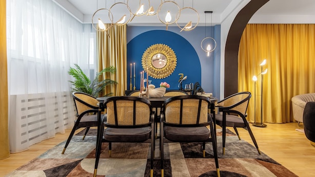 A dining area with a round table, chairs, and a decorative mirror. - Birds of Paradise (Bucharest)