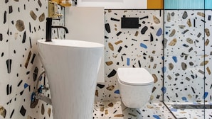 A bathroom with a white sink, a toilet, and a shower area. - Birds of Paradise (Bucharest)