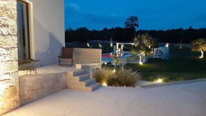 Un patio moderno al aire libre con un muro de piedra, una silla de descanso y una pequeña mesa.