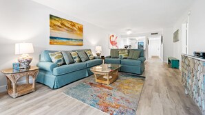 A modern living room with a sectional sofa, a glass coffee table, and a colorful rug. - Siesta Dunes 6-102, Peaceful Garden View Unit, 2br/2ba, 1st Floor Condo (Sarasota)