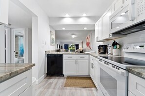 A modern kitchen with white cabinetry, a dishwasher, an oven, and a microwave. - Siesta Dunes 6-102, Peaceful Garden View Unit, 2br/2ba, 1st Floor Condo (Sarasota)