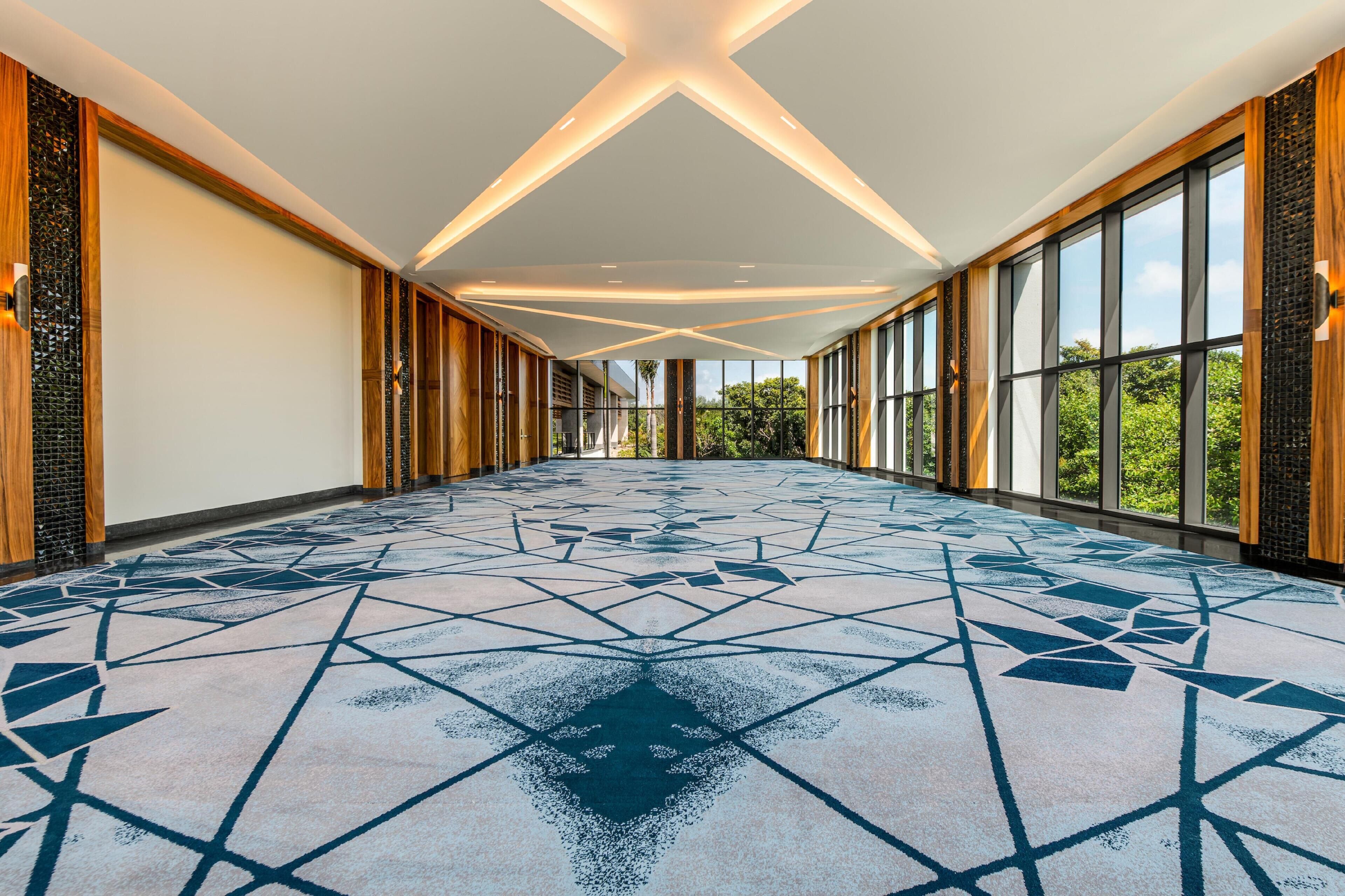 Un pasillo espacioso con un elegante piso de estampado geométrico, ventanas amplias y paneles de madera.