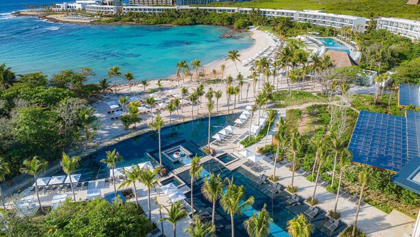 Un resort con varias piscinas, una playa y vista al océano.